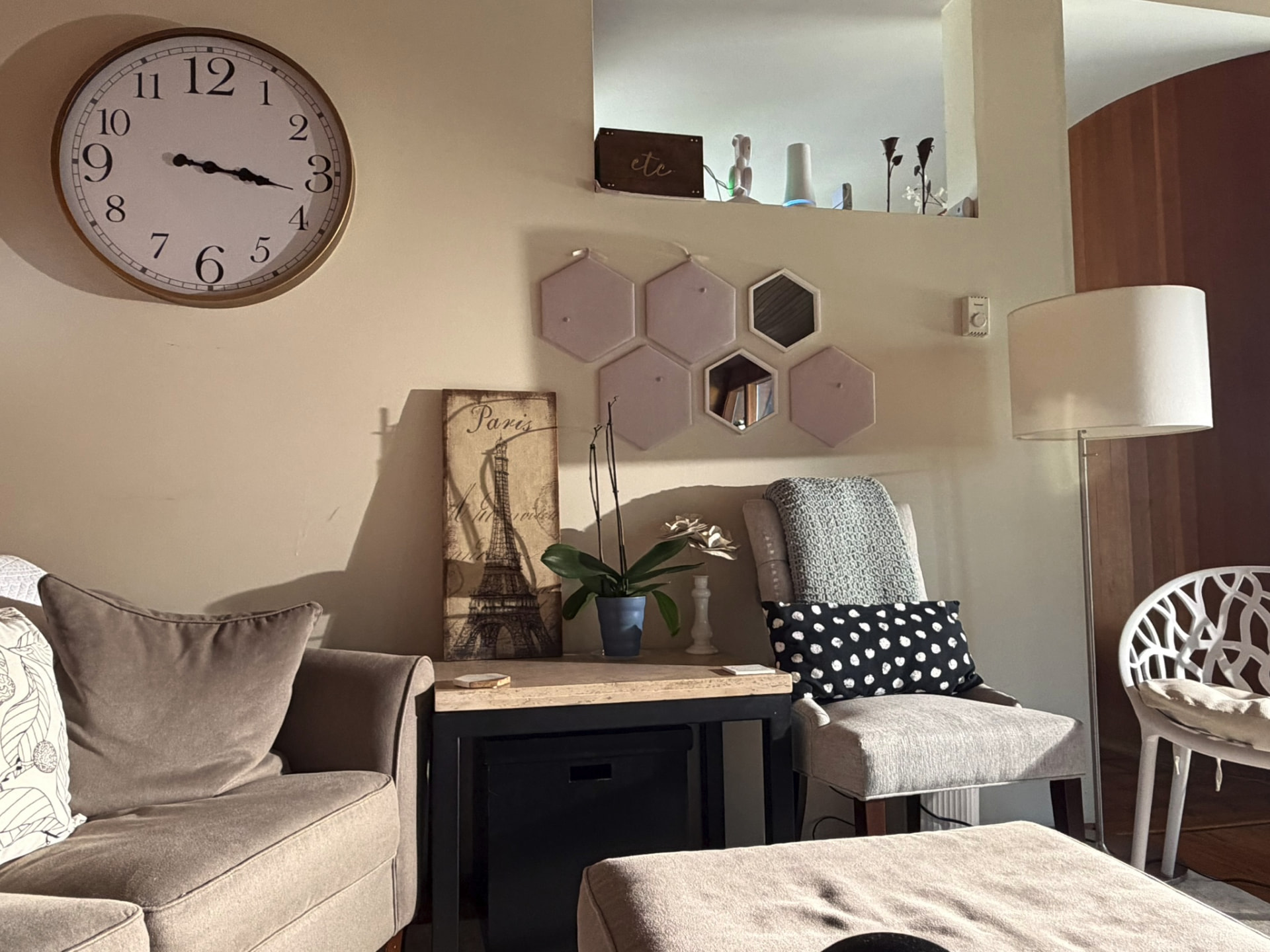 Quiet corner of the studio with a clock, a chair, and an orchid