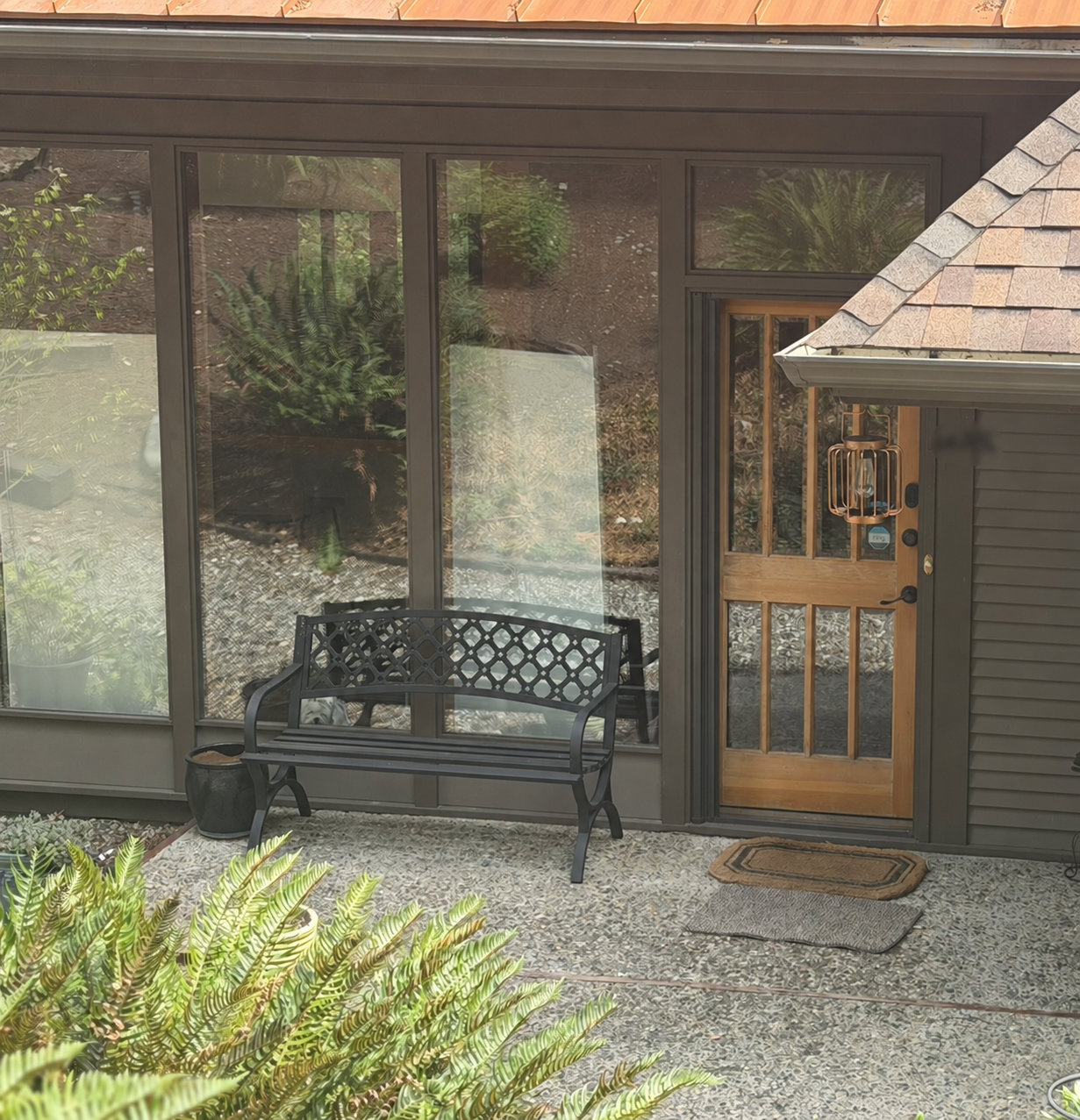 Entrance to Confident Core Studio, with a bench, ferns, and a wooden door
